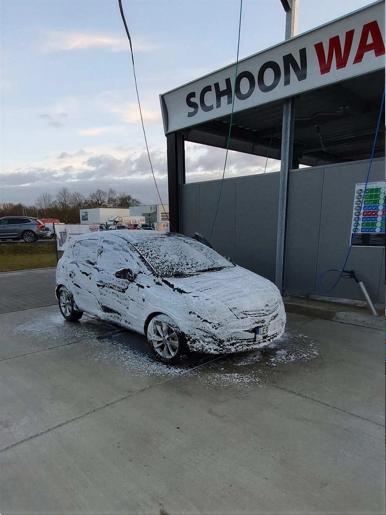 Eingeschäumtes Auto vor dem Schoon-Wash-Schild